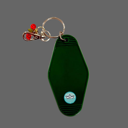 Green keychain with a small boat logo on a white background