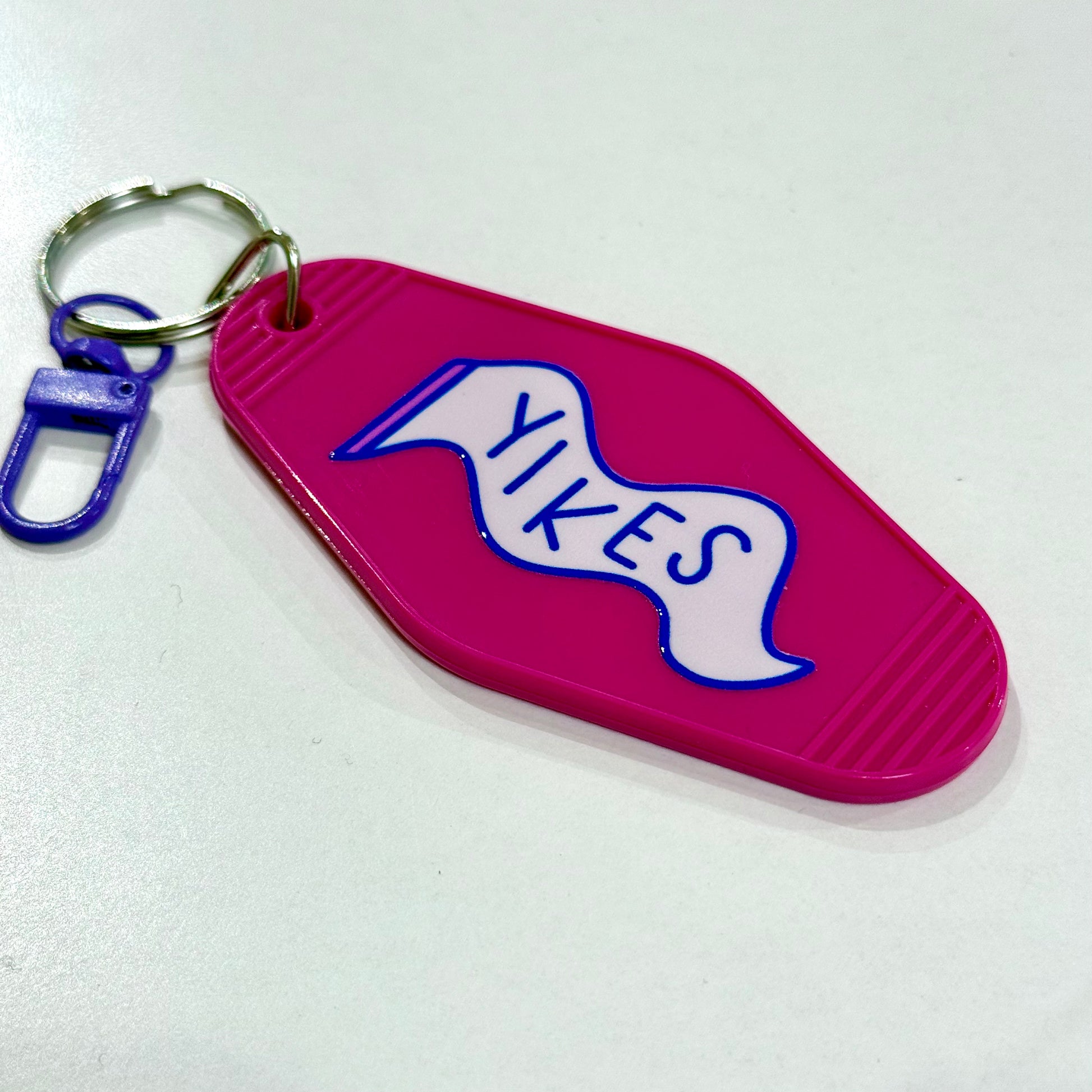 Pink keychain with 'YIKES' text on a white background