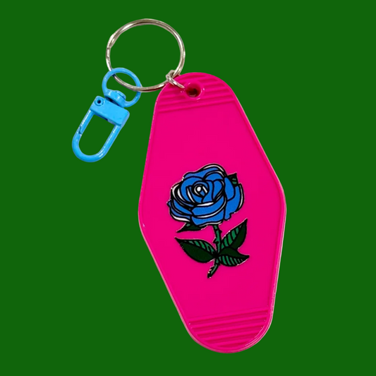 Pink keychain with blue rose design on a green background