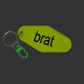 A lime green keychain tag with the word 'brat' printed in black lowercase letters, attached to a silver split ring and a green lobster clasp, shown on a dark gray background.