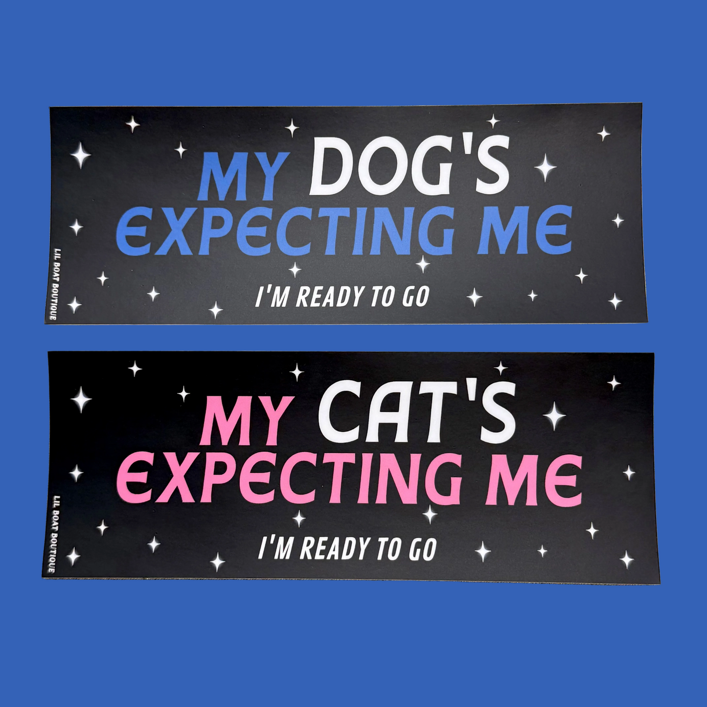 Two rectangular bumper stickers shown on a solid blue background. The top sticker reads 'MY DOG'S EXPECTING ME I'M READY TO GO' in blue and white text on a black background with white star graphics.